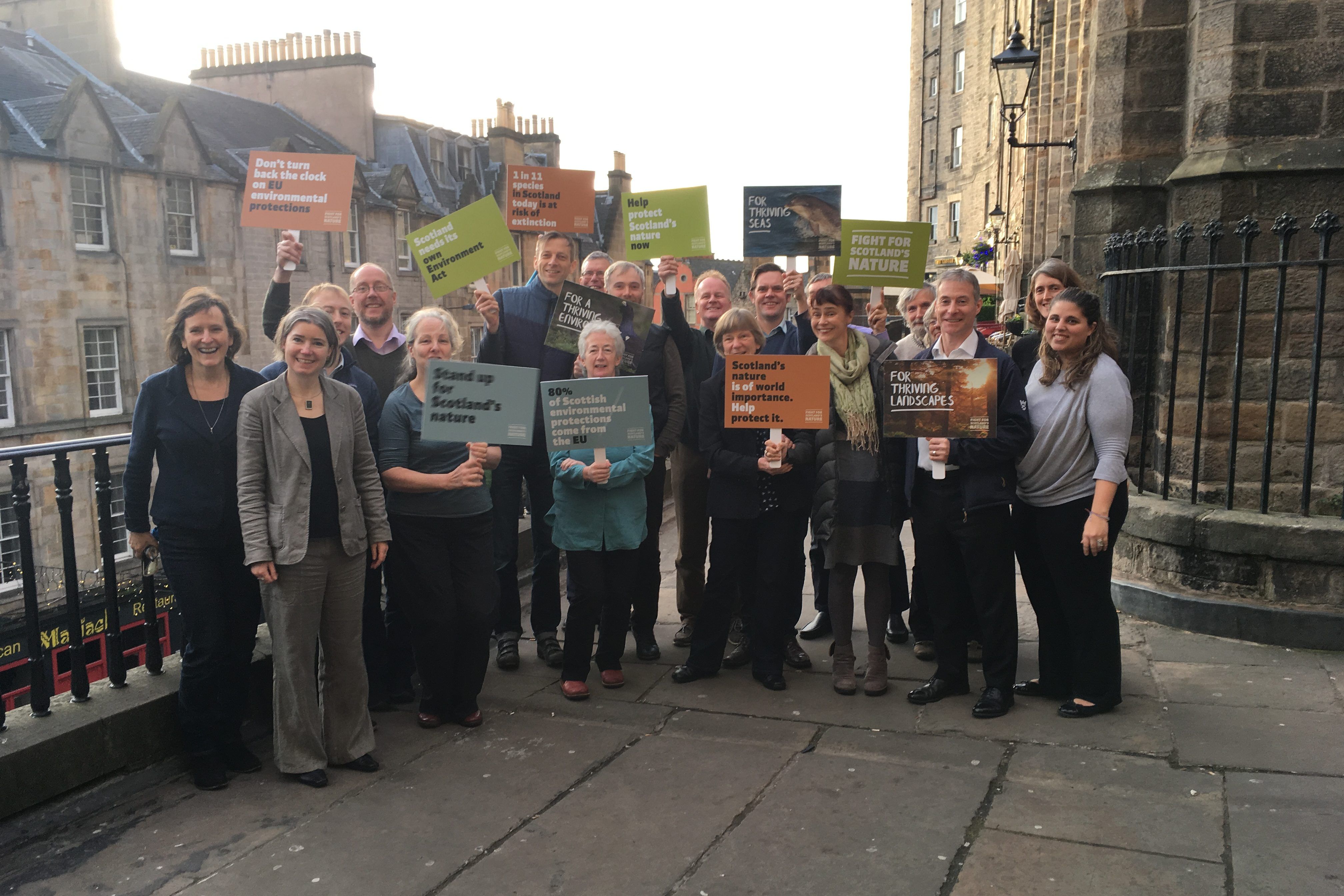 Scotlink staff and campaigners outside in Edinburgh holding campaign banners.