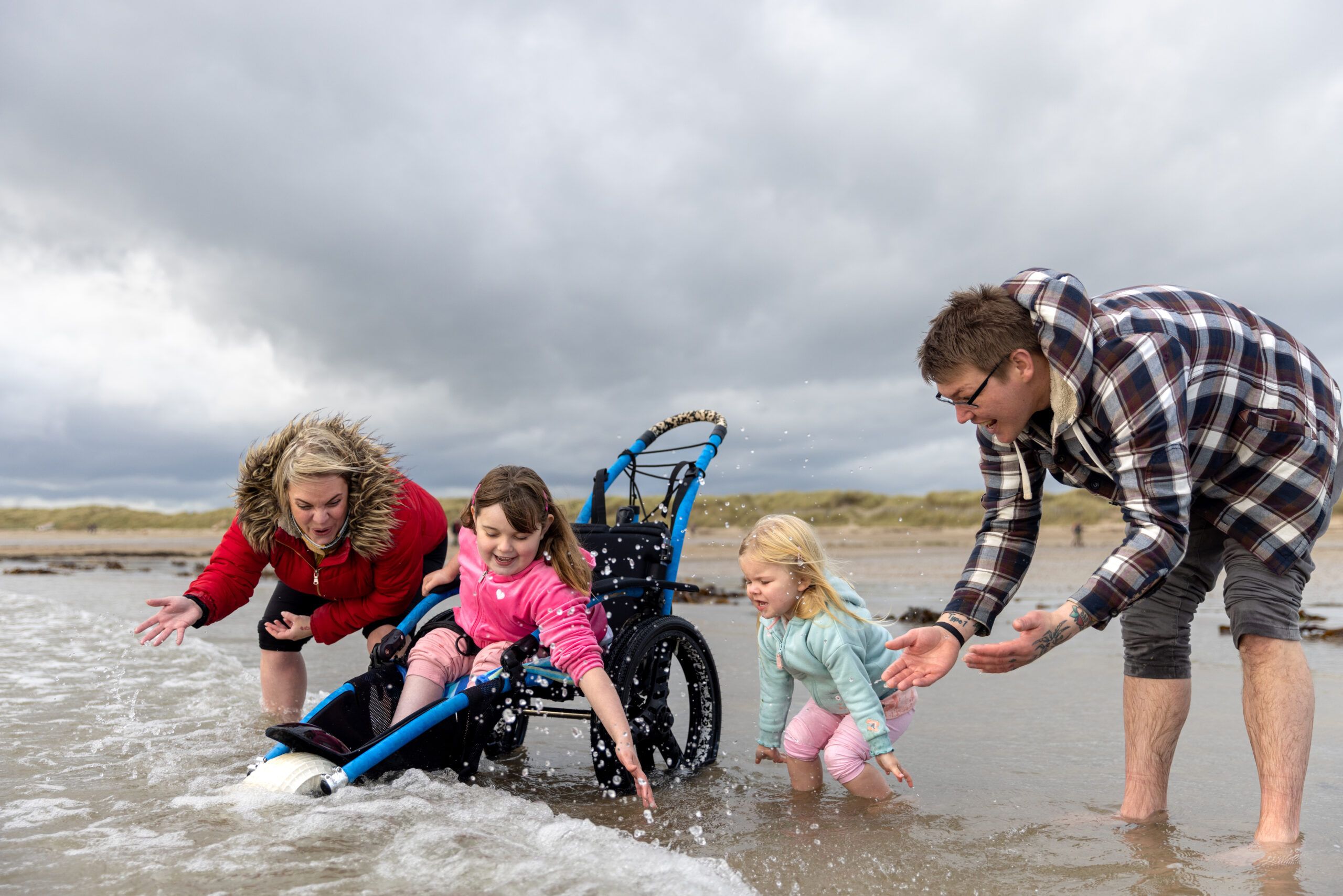 a family playing in the ocean with a child in a wheelchair