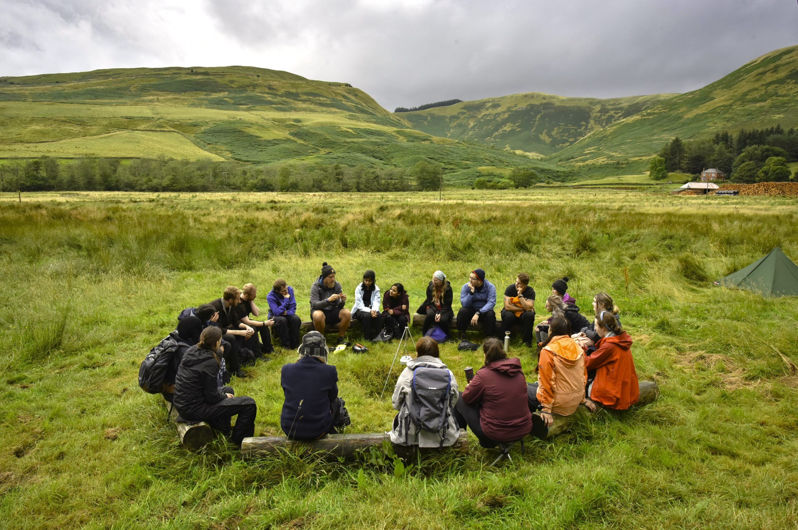 a group of people sitting around a circle in the middle of a field