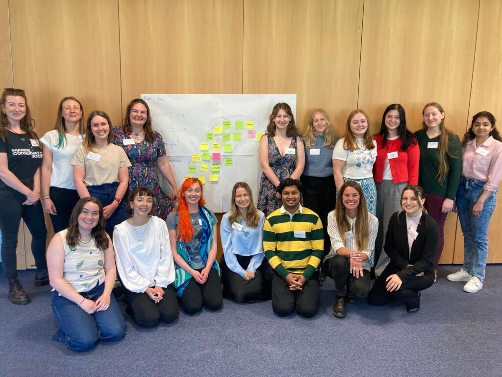 a group of people posing for a photo in front of a poster board